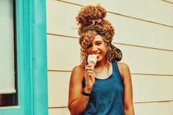 Happy Black female snacking on an ice cream cone in the sun