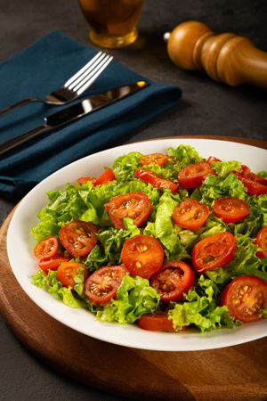 Bowl of sliced tomatoes on bed of lettuce, vertical