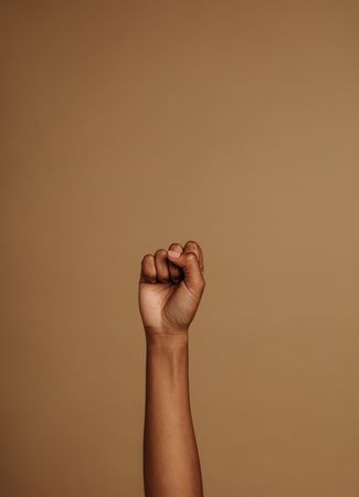 Fist held tightly against brown background