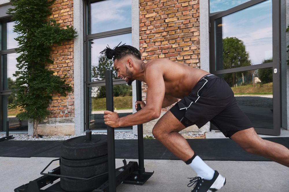 Black guy pulling weights in outdoor gym