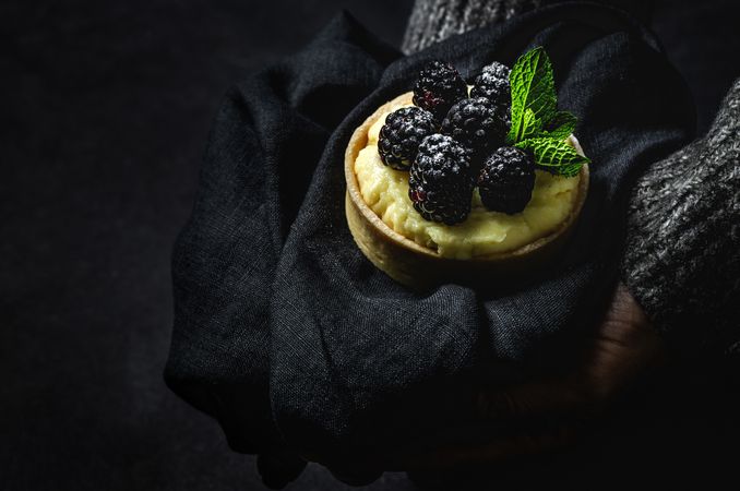 Hand holding a blackberry tartlet