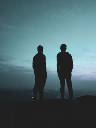 Silhouette of two men standing on hill
