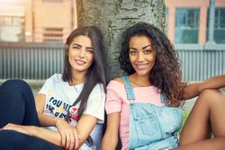 Attractive young females sitting outdoors and smiling at camera