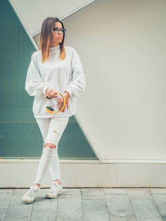 Young woman with headphones standing against wall