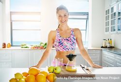 Smiling woman in bright kitchen making juice 0vdnZ4