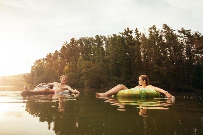 Portrait of young couple in lake on inflatable rings