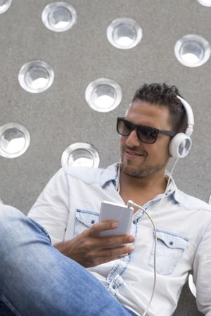 Happy male using headphones while holding phone