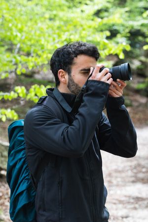 Traveling man taking photo on camera in woods