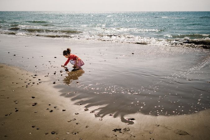 Girl playing with little stones on beach