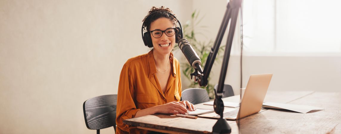 Female podcaster looking at the camera and smiling while working from home