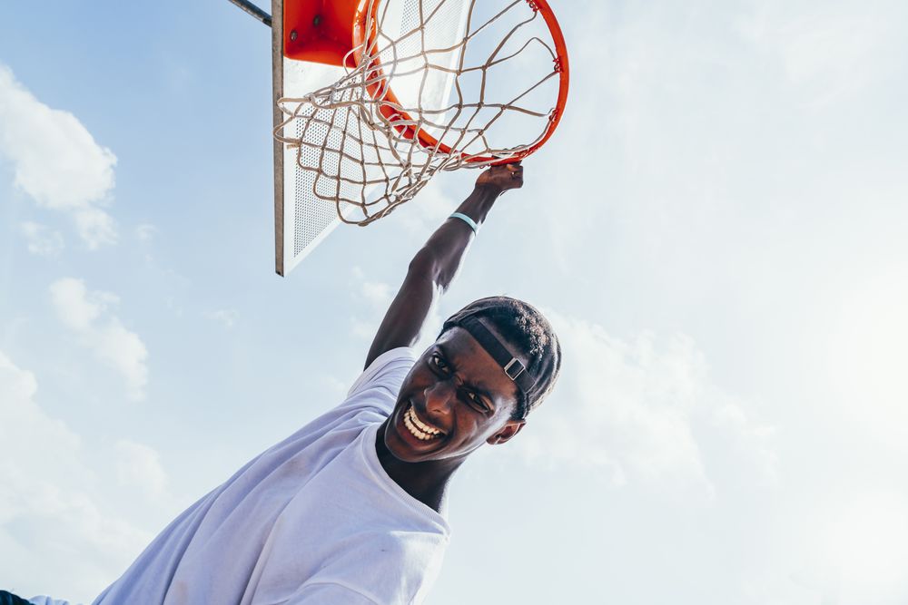 Black sportsman hanging on basketball lap