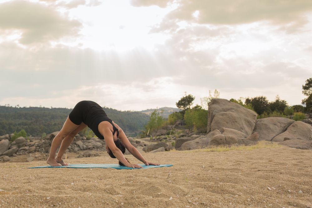 Woman practicing yoga outdoors near water