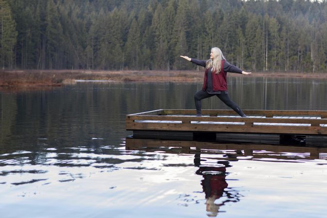 Mature woman practicing yoga on lake dock