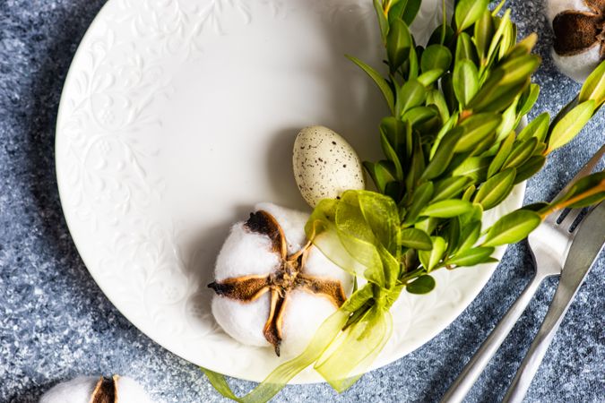 Top view of Easter table setting with branch, cotton and decorative eggs