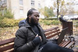 Black Young Man Using Laptop for Online Conversation in Park.