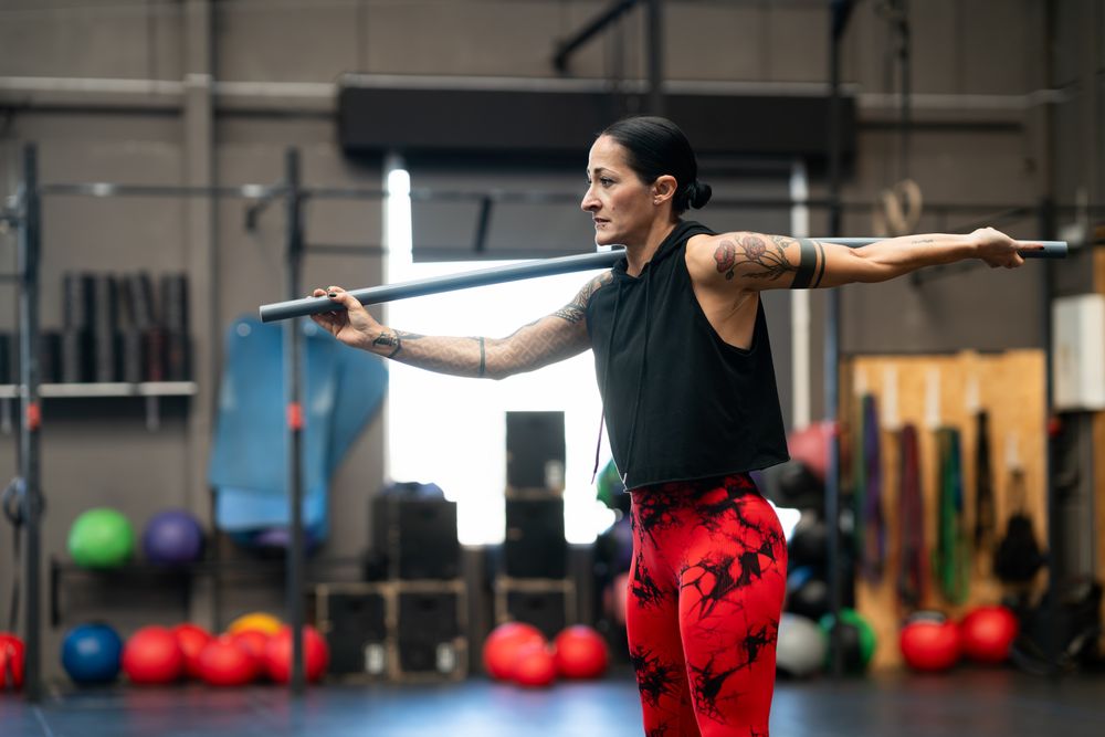 Woman stretching with bar in gym before workout