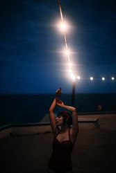 Mysterious woman in retro swimsuit dancing under streetlamp