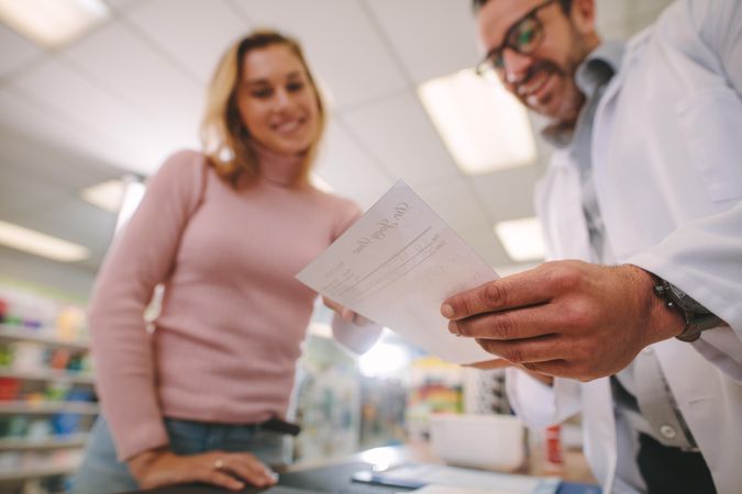 Male pharmacist helping female customer at pharmacy