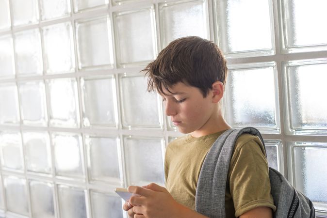 Tired teenager texting while leaning on wall