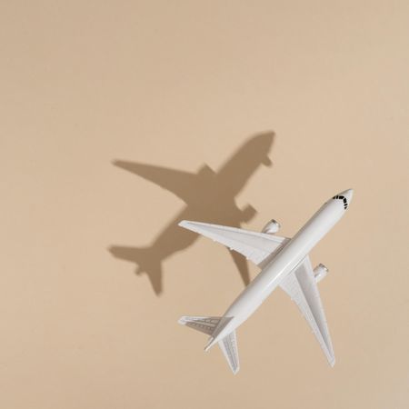 Top view of model airplane with shadow over beige paper