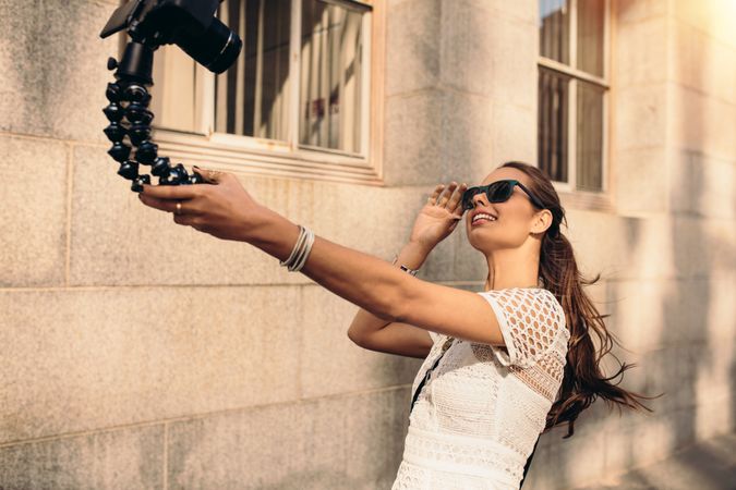 Beautiful woman holding flexible tripod taking a selfie