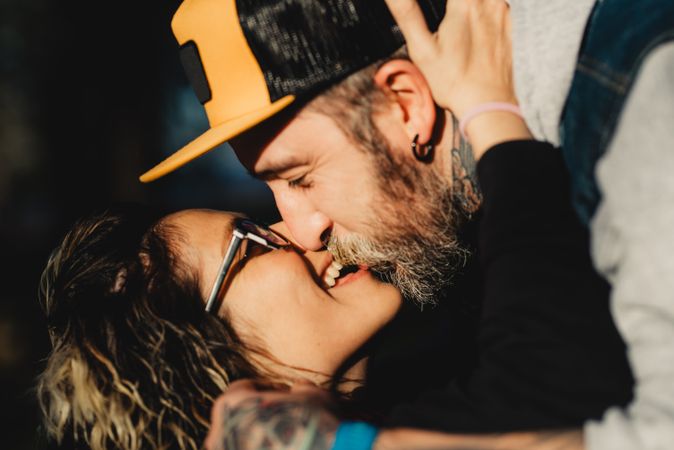 Happy couple hugging and kissing near tree in park
