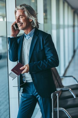 Businessman standing at waiting lounge in airport and using mobile phone