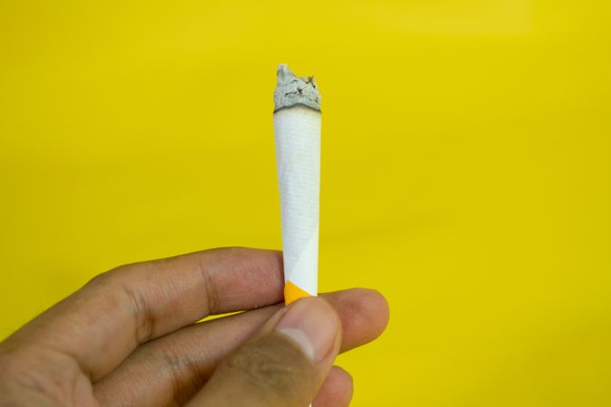 Side view of hand holding lit cigarette