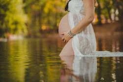 Pregnant woman standing in lake water