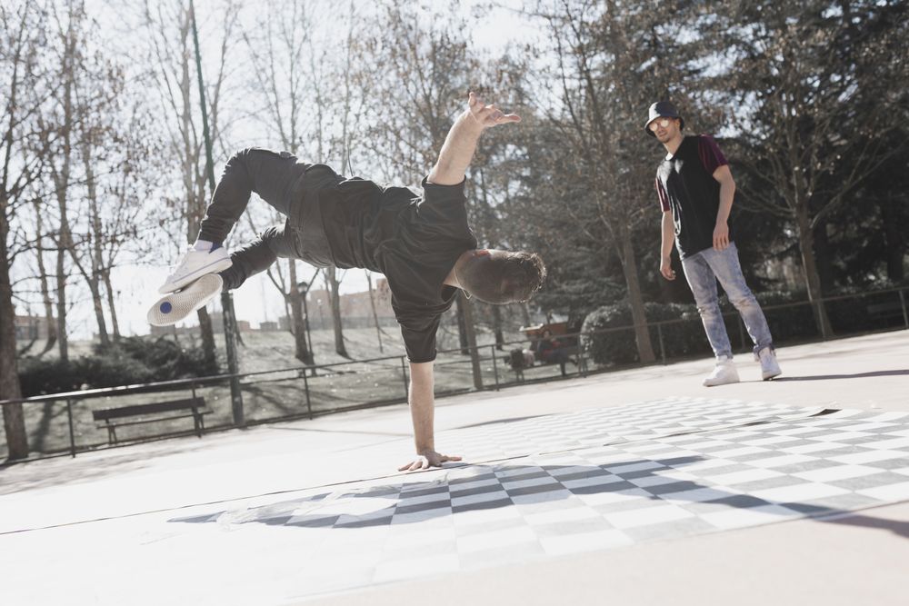 Guy looking at man dancing break dance in park