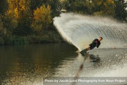 Sporty male using one water ski on calm lake 4BQQ35