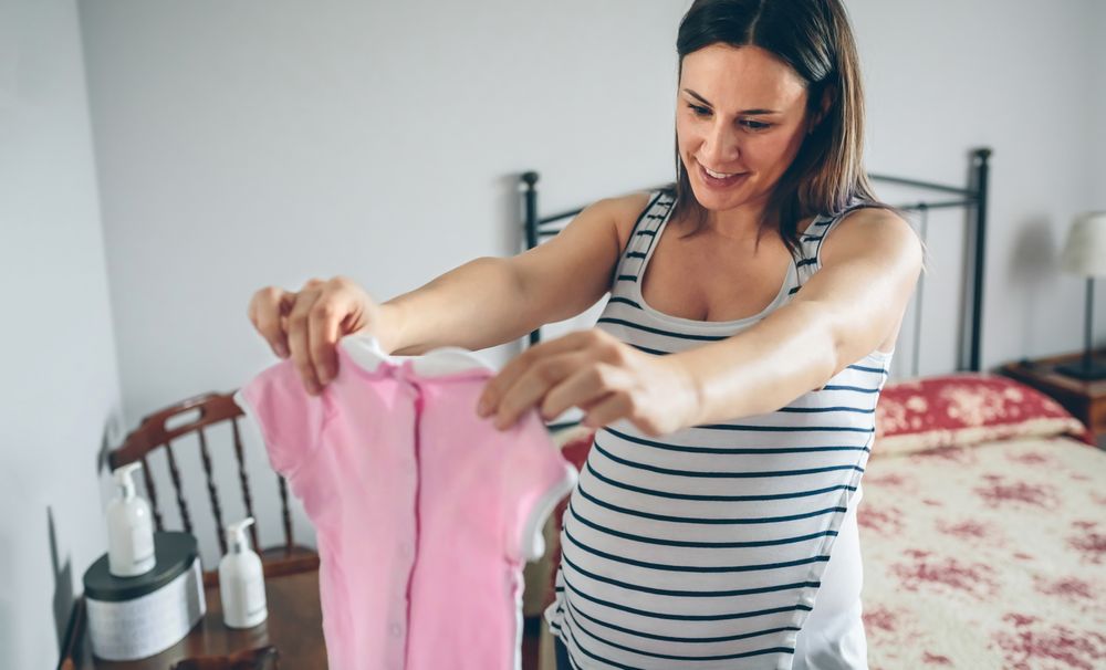 Pregnant looking at baby girl dress