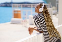 Smiling female relaxing on pier listening to music