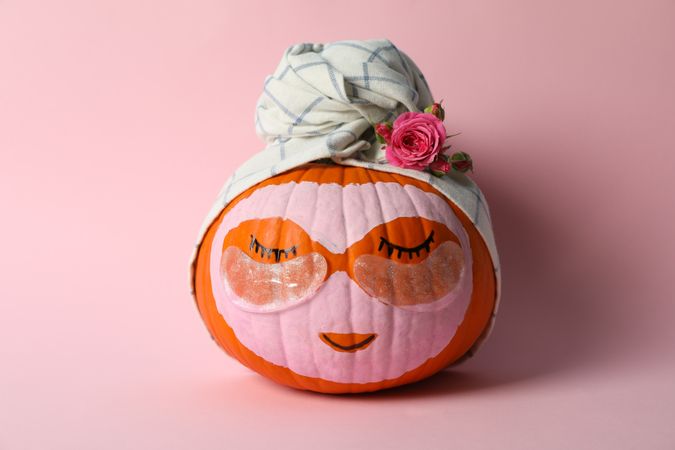 Pumpkin with eye patches and towel on pink background