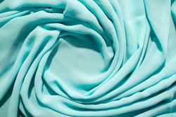 Spiral Twisted Turquoise wavy crumpled fabric with little sparkling dust and copy space in center, texture and  background.