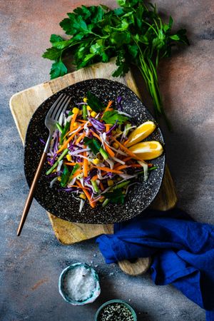 Top view of fresh salad with finely chopped vegetables and lemon slices in bowl on counter with copy space