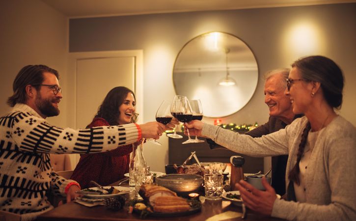 Family at dining table for Christmas dinner toasting with wine
