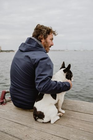 Man and dog resting on pier together
