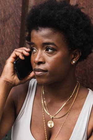 Smiling Black woman talking on smartphone sitting near building