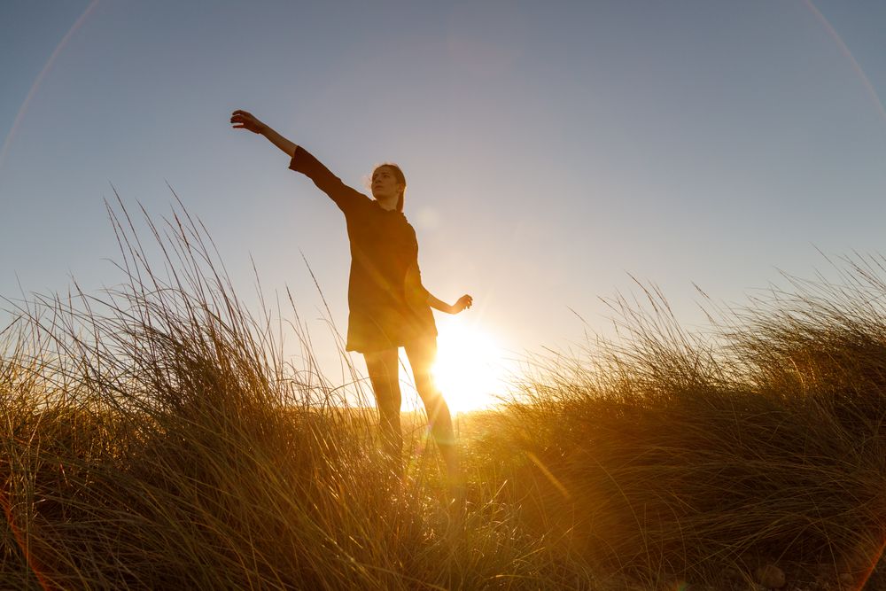 Woman posing between field at sunset