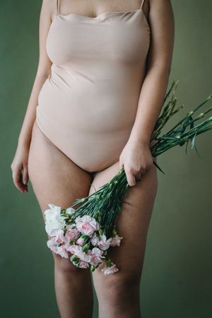 Woman in beige leotard holding a bouquet of flowers