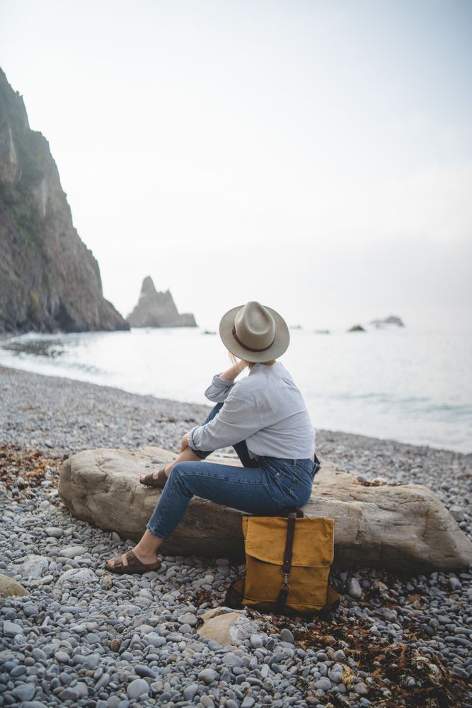 Woman resting on beach stone by sea