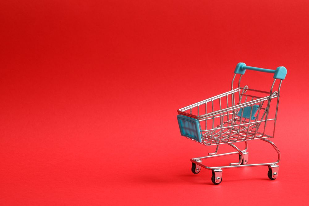 Blank shop trolley on red background, space for text