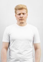 Monochrome: Portrait of an albino Latino man in light clothing against a light background.