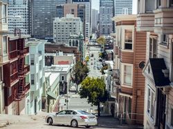 Car on city street with modern buildings in summer
