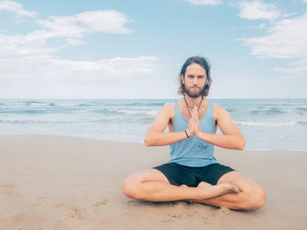 Man training yoga on beach