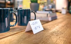 Close up of articles price label over wooden counter in local store with industrial style decoration