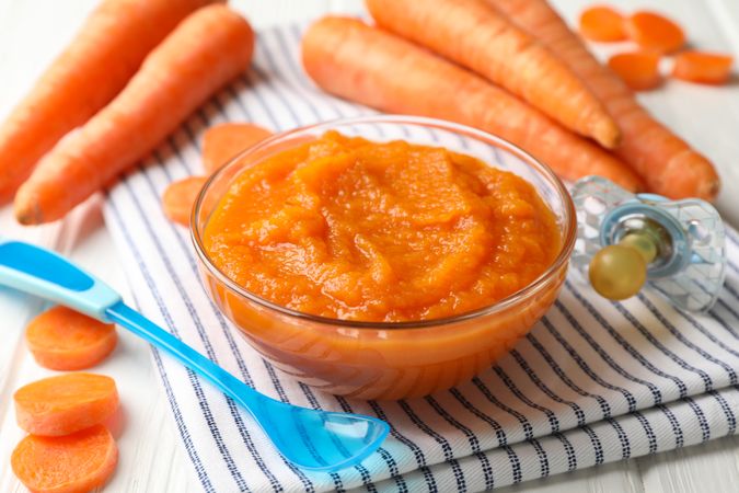 Composition with carrot puree on wooden background. Baby food