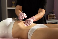 Gloved hands gently massage abdomen after honey application.