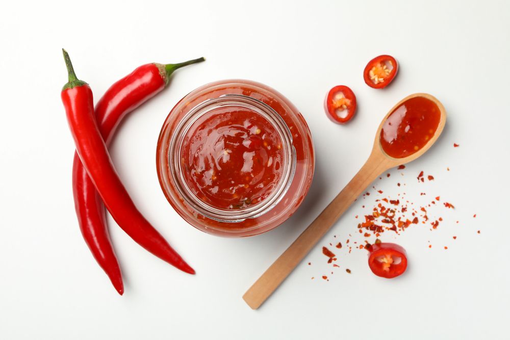 Composition with chilli pepper, spice and sauce on studio background